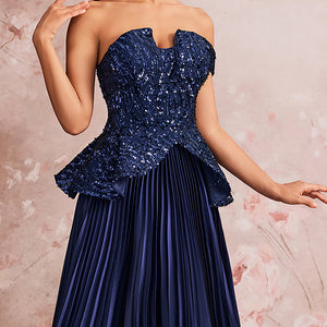 Close-up detail of a peacock blue off-the-shoulder evening gown, highlighting the sparkling floral sequin bodice, sweetheart neckline, and peplum waist.