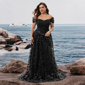 Side profile of a model in a sweeping A-line gown by the ocean. Ideal semi formal evening wear for special occasions.