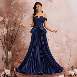 A full-body view of a model wearing a peacock blue off-the-shoulder sequin evening gown with a peplum waist