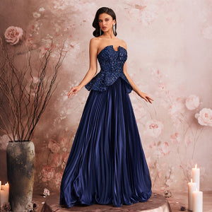A model wearing a peacock blue off-the-shoulder floral sequin gown, posing in a romantic room with dried flowers and candles, perfect for wedding guests.